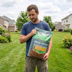 Man holding a package of Schultz Once & Done lawn repair product in a grassy area.