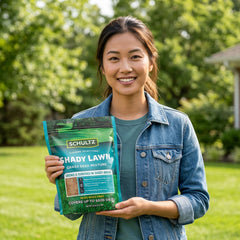 Woman holding a package of Schultz Shady Lawn grass seed mixture in a garden setting